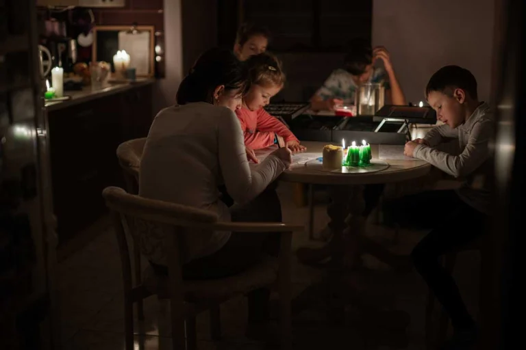 A family coloring and painting by candlelight because the power is out.|A portable, backup generator with cans of fuel outside a garage with snow all around|A Generac standby generator ready to work while covered in ice, rain, and snow.