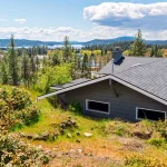 A view out to Lake Coeur d'Alene up on a hill from above and behind an older home slightly down the mountain|Plug-in carbon monoxide detector installed for home safety during HVAC upgrade|Honeywell thermostat installed to control new HVAC system in Spokane Valley home|New high-efficiency furnace installed in Spokane Valley home basement|New outdoor AC unit installed on pad next to Spokane Valley home