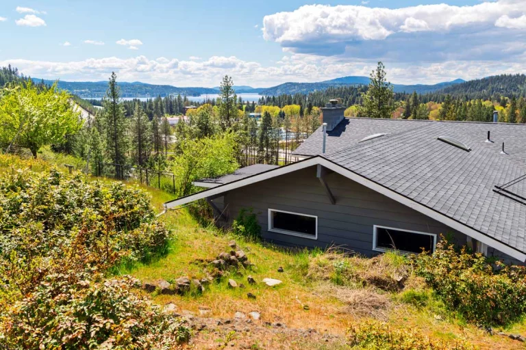 A view out to Lake Coeur d'Alene up on a hill from above and behind an older home slightly down the mountain|Plug-in carbon monoxide detector installed for home safety during HVAC upgrade|Honeywell thermostat installed to control new HVAC system in Spokane Valley home|New high-efficiency furnace installed in Spokane Valley home basement|New outdoor AC unit installed on pad next to Spokane Valley home