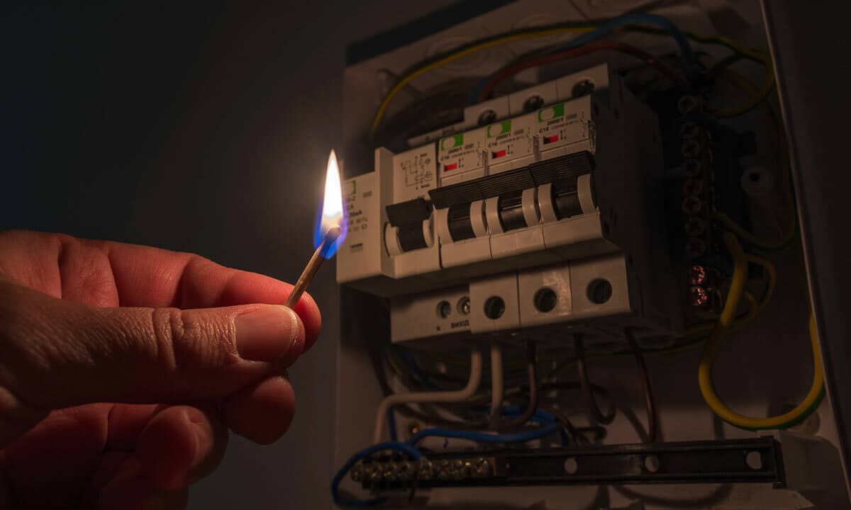 Someone using a match to look at the electrical panel during a blackout