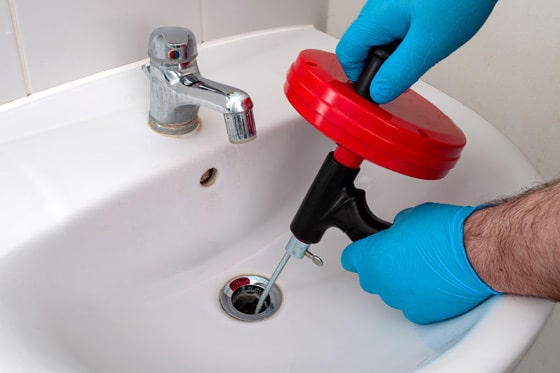 Plumber using an auger or snake on a drain