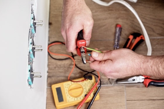 An up close image of a person testing the voltage of wires in a home