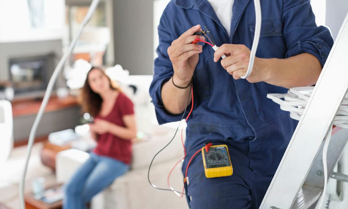 An electrician working while the homeowner watches