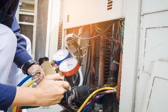 An up close image of an HVAC technician testing an HVAC unit with tools