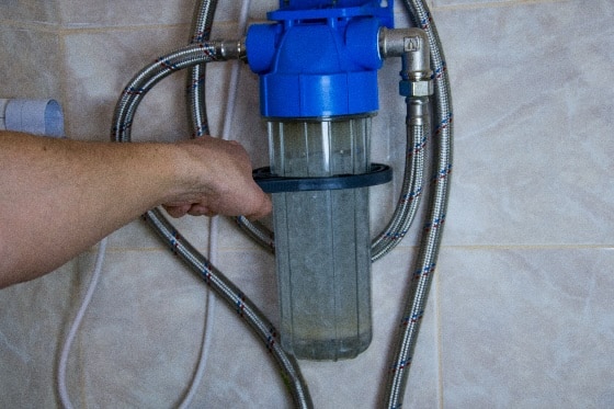 A person tightening a water conditioner container in a home