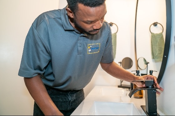 A Mainstream technician replacing a faucet in a bathroom sink
