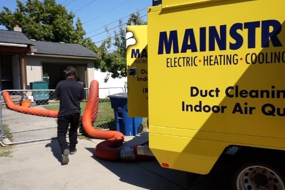 A photo of a Mainstream HVAC technician setting up the trucks and hoses for duct cleaning in a home