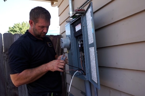 A Mainstream electrician working on an electrical panel of a home