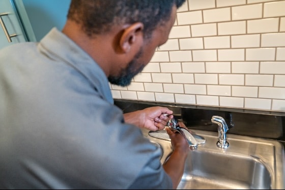 A photo of a Mainstream plumber replacing a faucet on a kitchen sink
