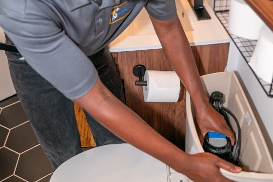A Mainstream plumber working on a toilet tank in a home