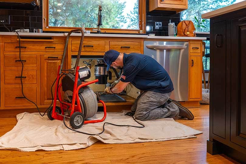 A Mainstream plumber working on a kitchen sink to clear a clog