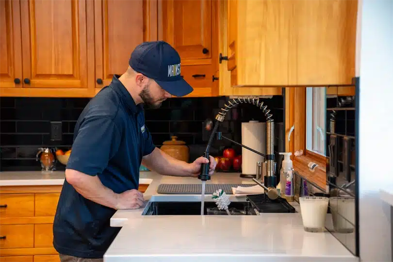 A plumber from Mainstream clears a clogged kitchen sink