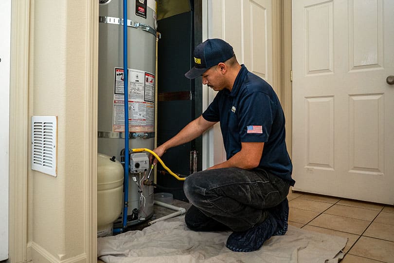 A Mainstream plumber flushing a water heater in a home