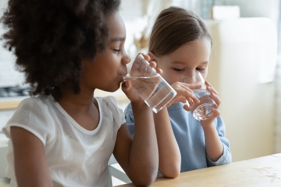 Two children drinking clean water from glasses