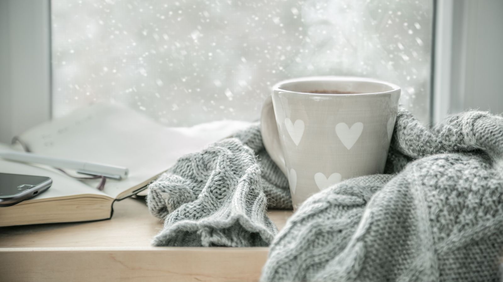 A warm mug wrapped in a blanked by a cold winter window