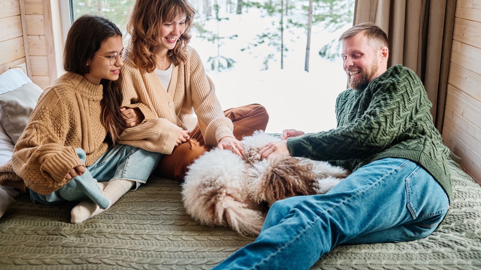 A family and their pet enjoying the indoors while it is snowing outside