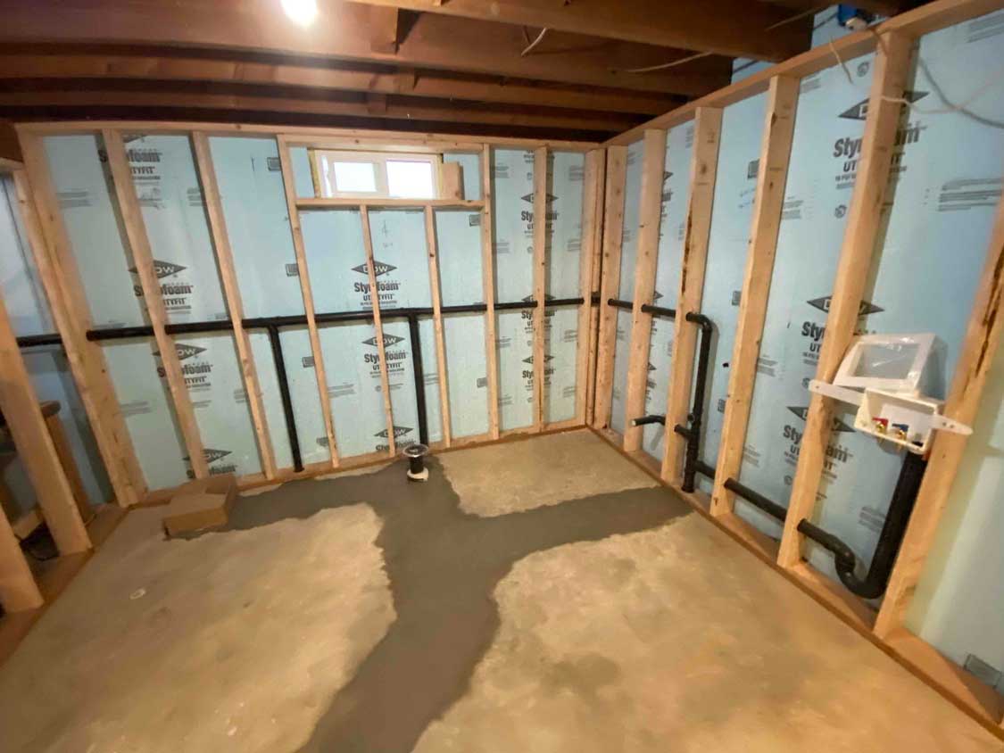 Basement plumbing repipe completed with concrete restored and new piping neatly installed behind framed walls.