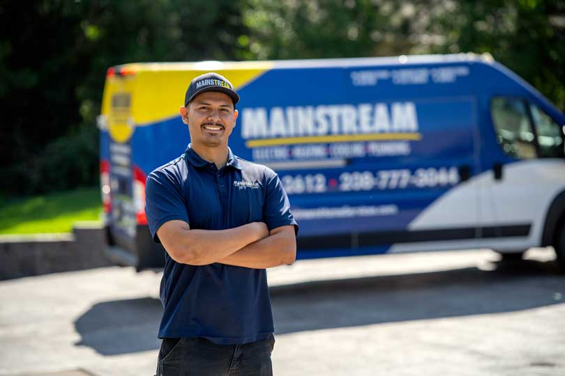 A Mainstream technician standing with his arms crossed in front of the work van