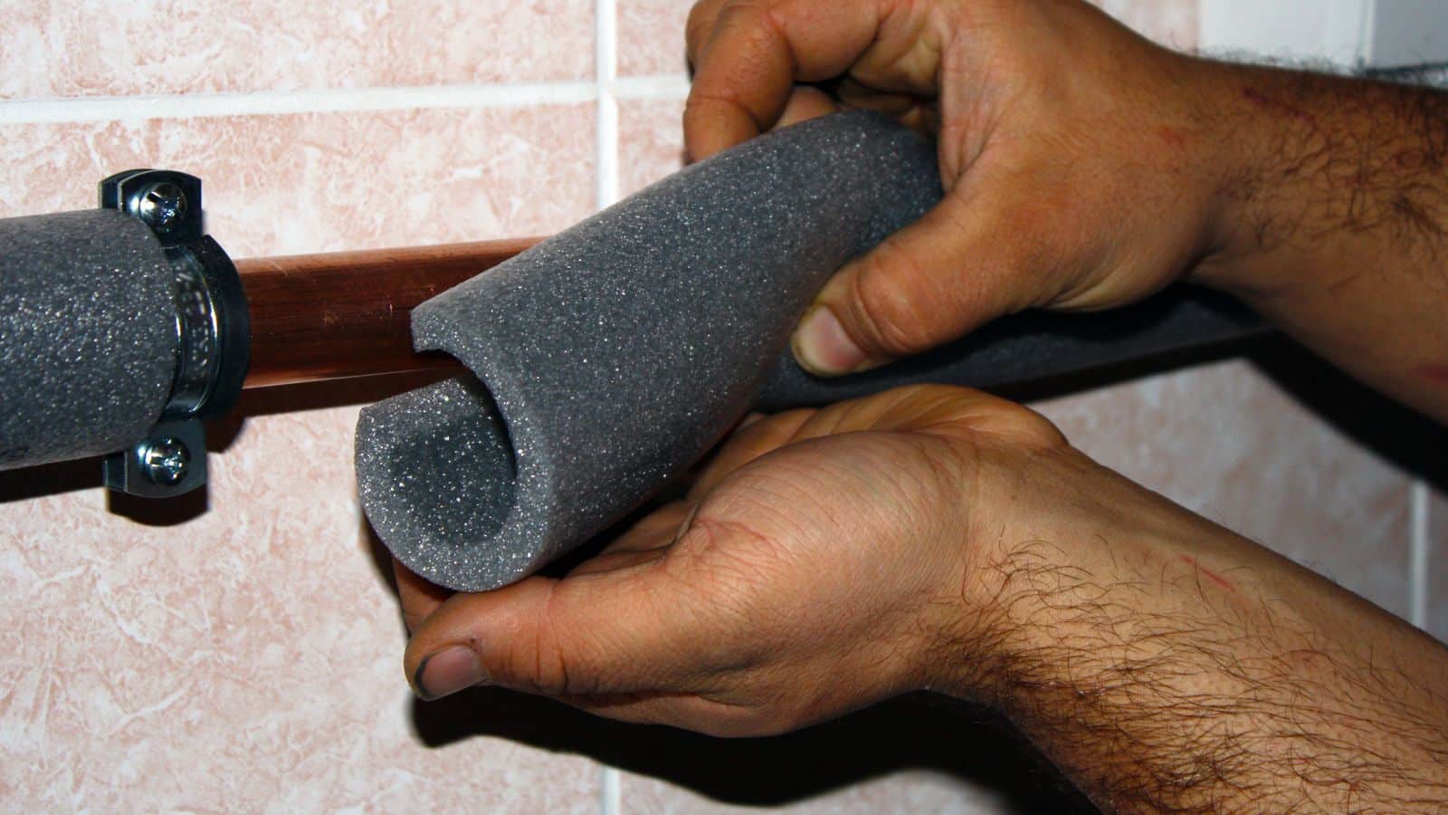 A person adding insulation to a copper pipe