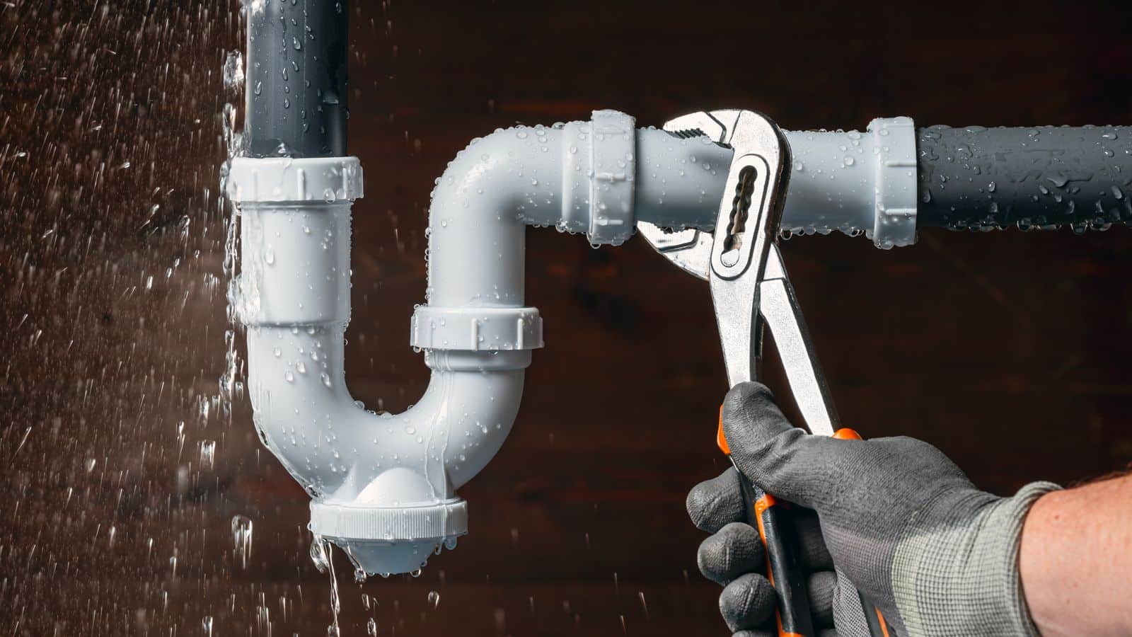 A plumber using a wrench to tighten a leaking pipe