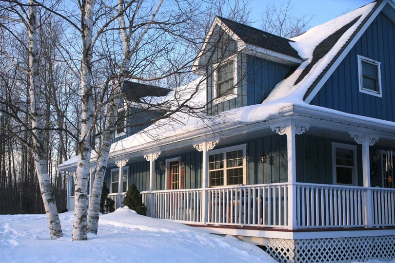 Single family home in the woods covered in snow.