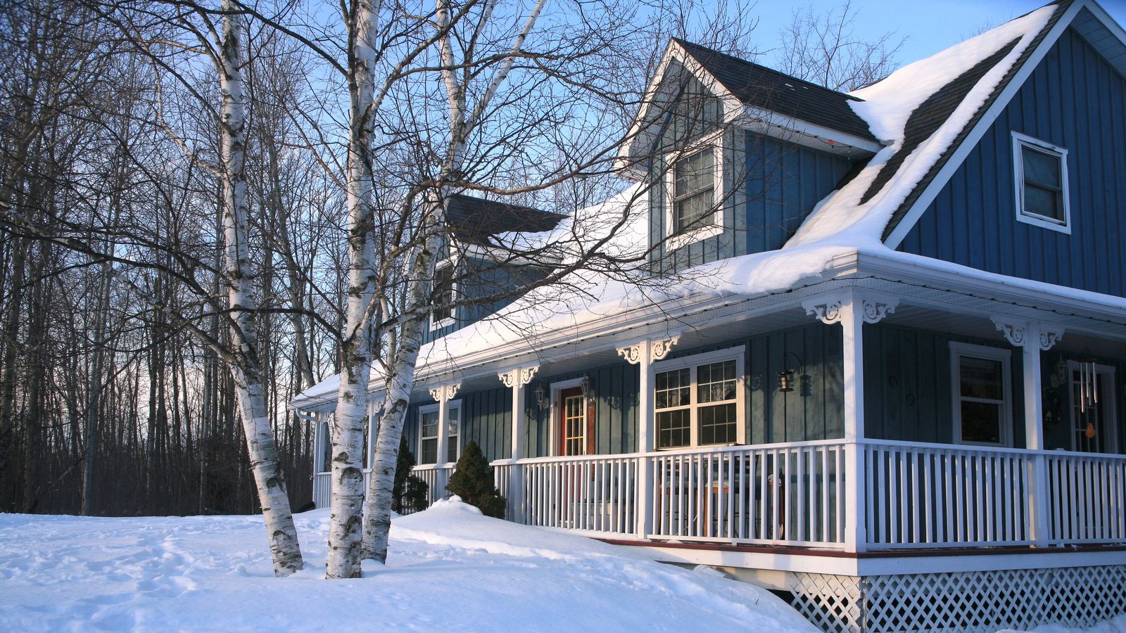 Single family home in the woods covered in snow.