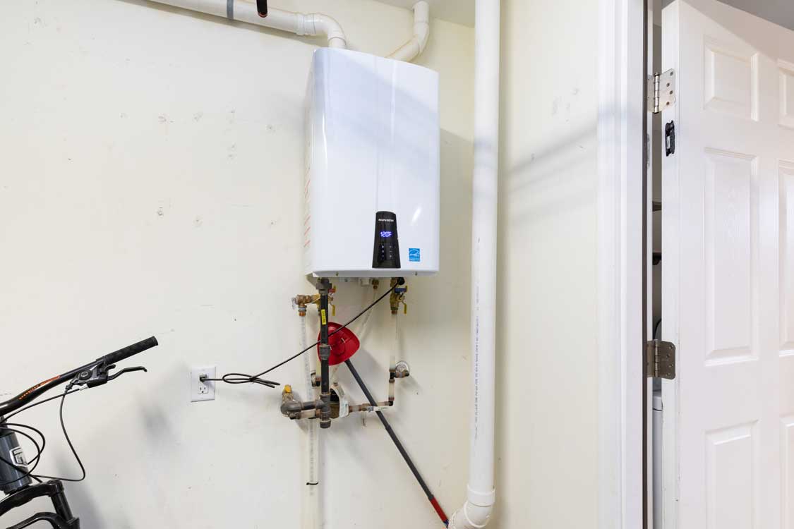 A recently installed tankless water heater on a wall in a home's garage